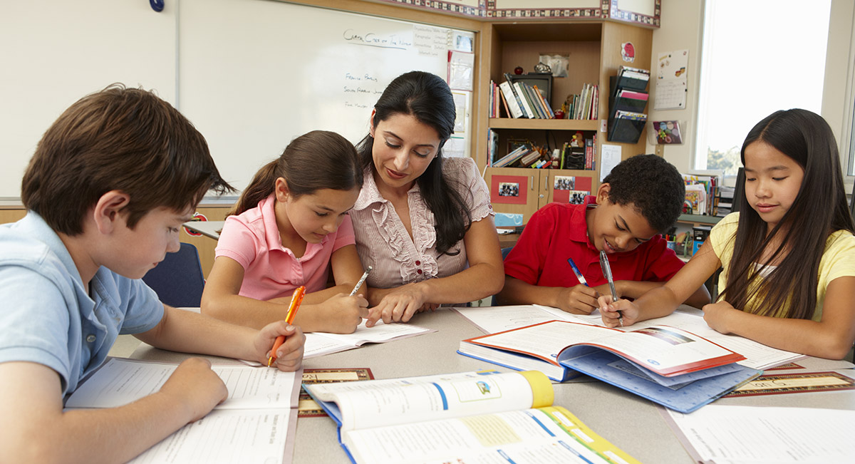 Teacher helping students in classroom Teacher working with group of students in classroom