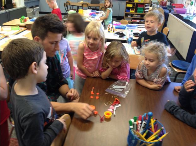 Noah L., a high schooler, completing a STEM bin challenge in one minute with the first grade class.