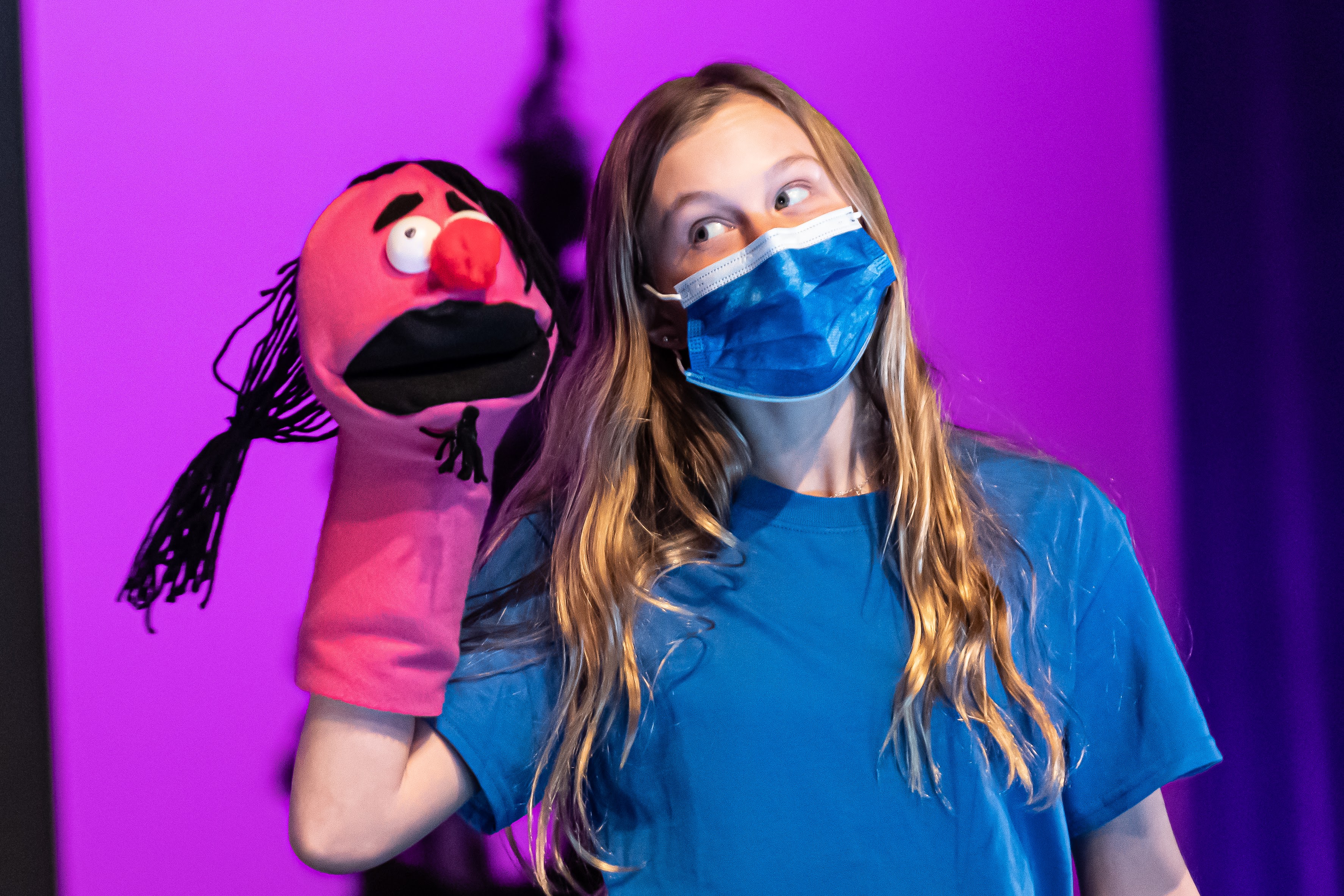 Student performing a puppet show wearing a face mask