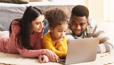 two parents help their child work on a laptop computer