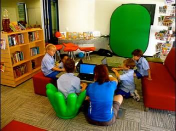 Elementary school students working together with computers at a library