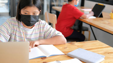 Students working at computers in school with masks