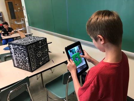 A student using a Merge Cube for three-dimensional modeling. 