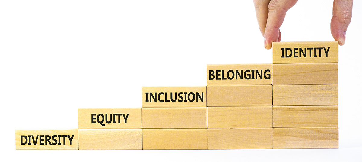 Wood blocks stacked into stairs with the words diversity, equity, inclusion, belonging and identity on the steps going up