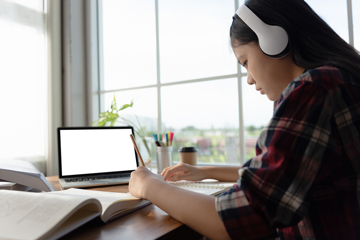 Student with headphones working on homework