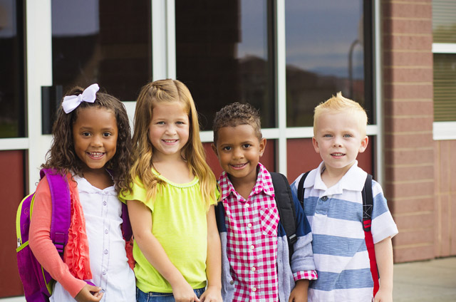 four young children standing together on the first day of school