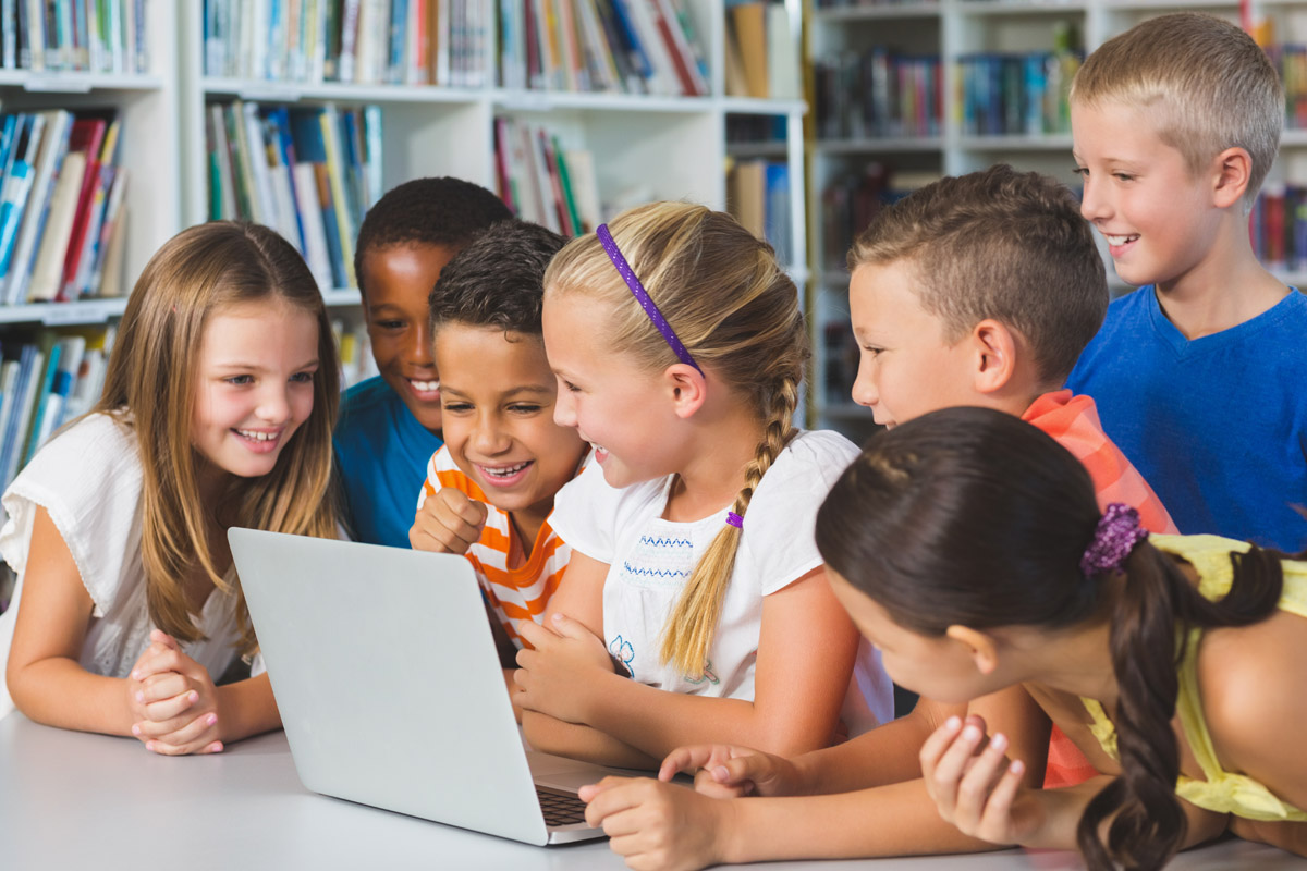 Young students gathered around computer.