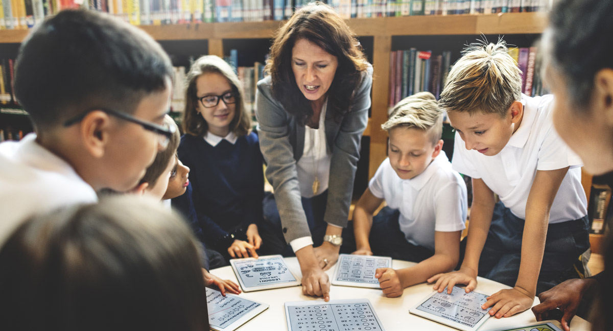 School teacher teaching students at a table.