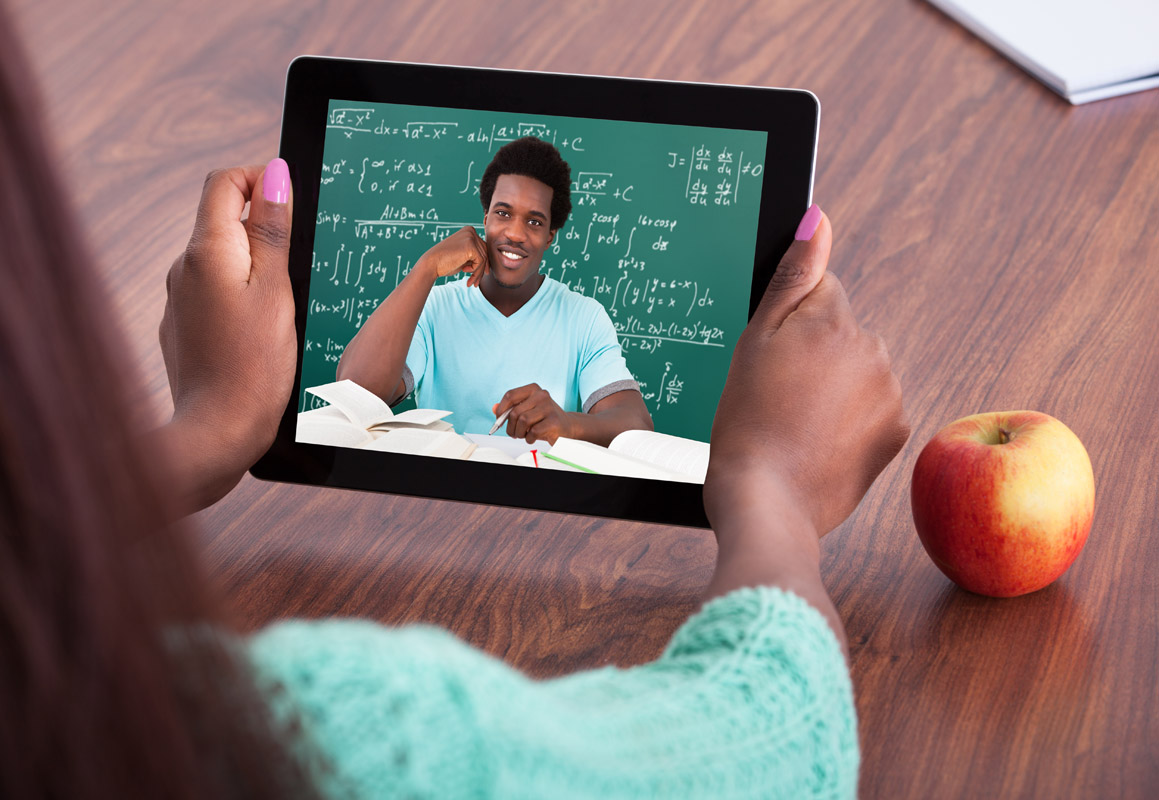 Student holding a tablet showing image of teacher