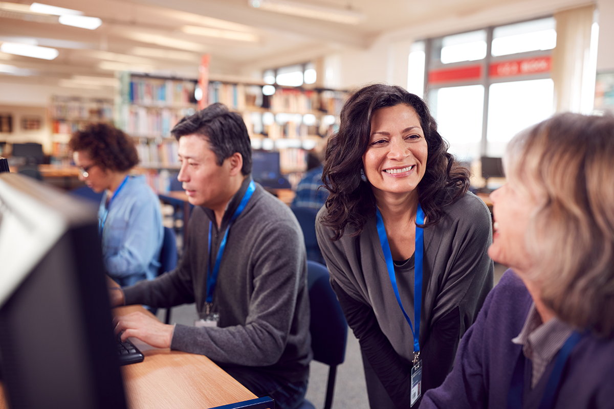 Group of teachers working at computers in library