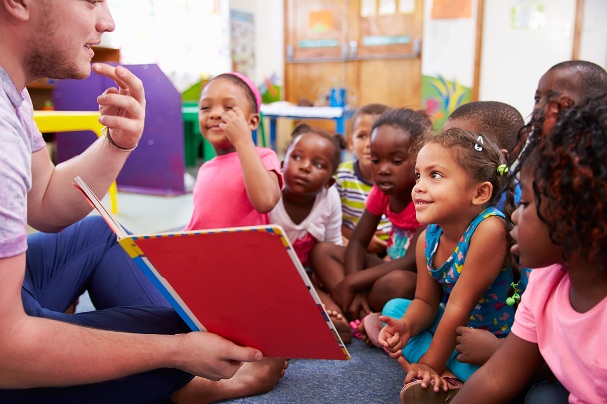 Preschool students listening to a teacher read aloud.