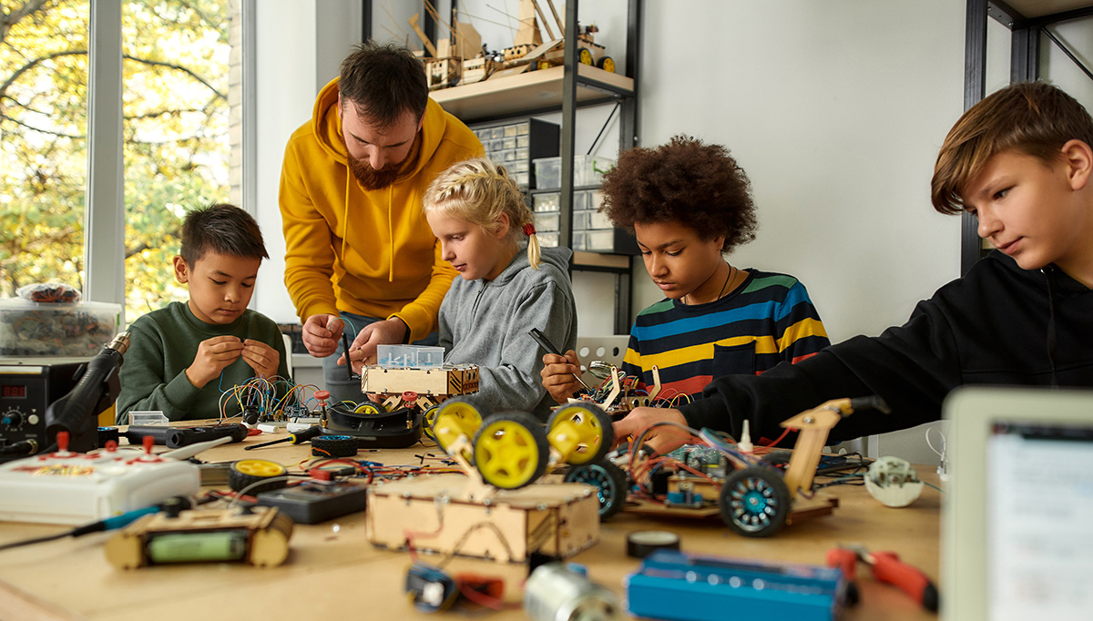 Teacher helping students to build a robot