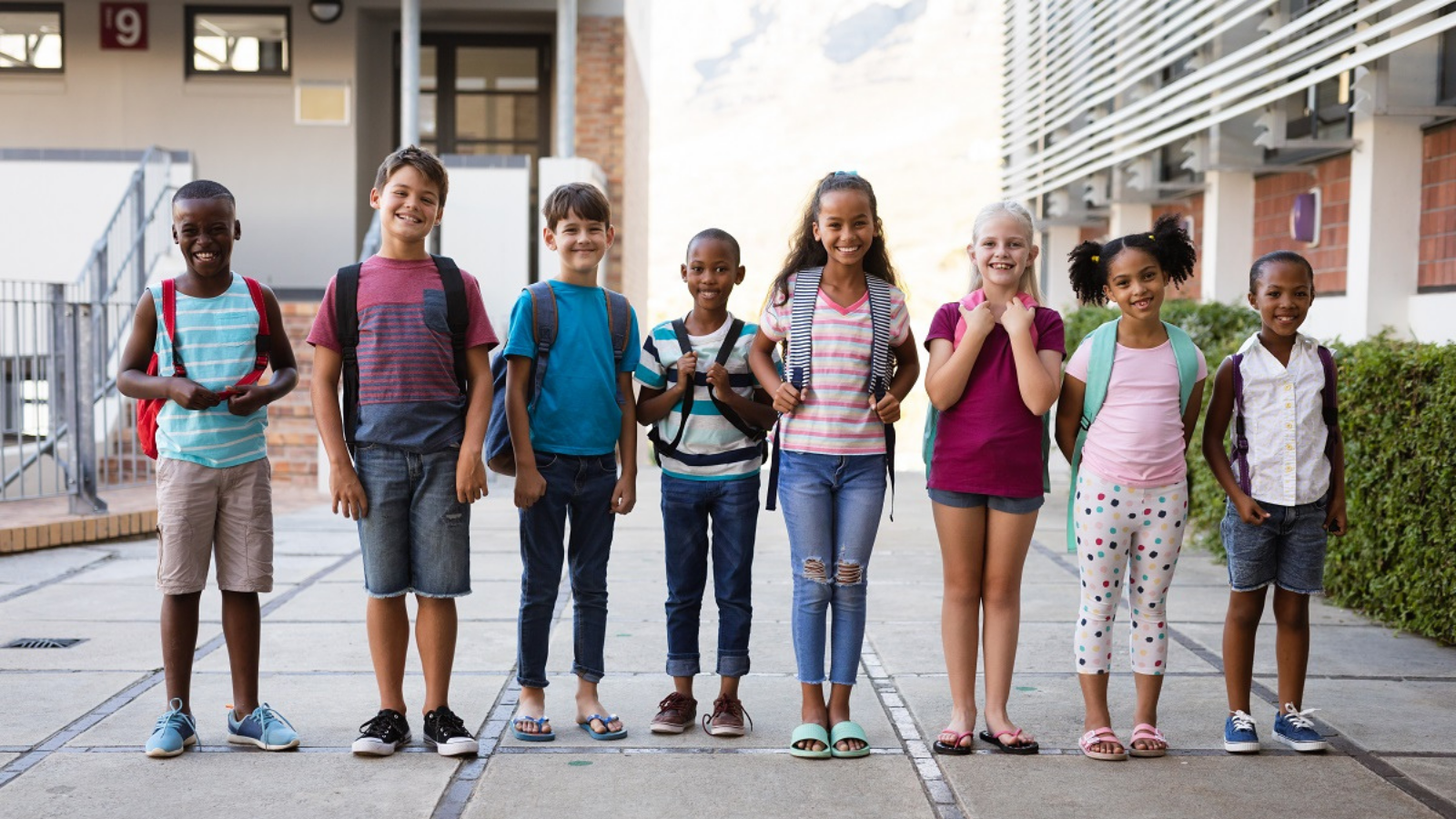 group of smiling students outside with backpacks