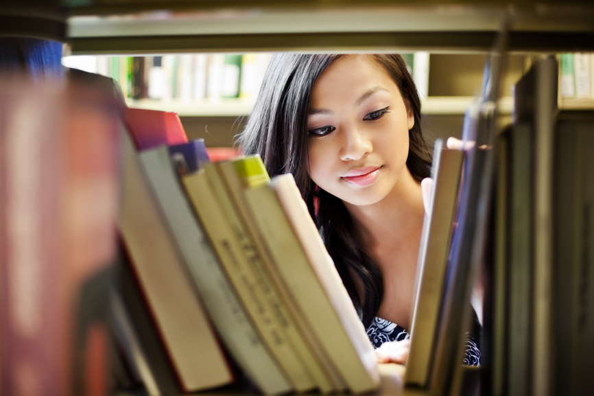 Student looking for books in a library