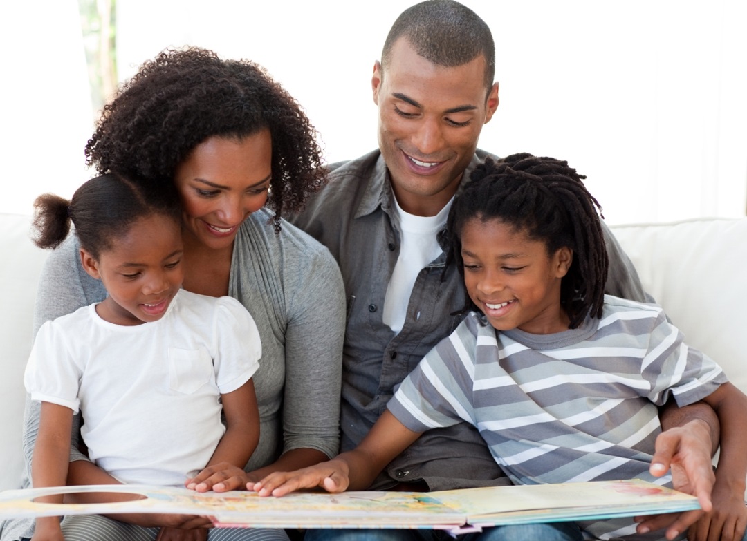 family of four reading a book together