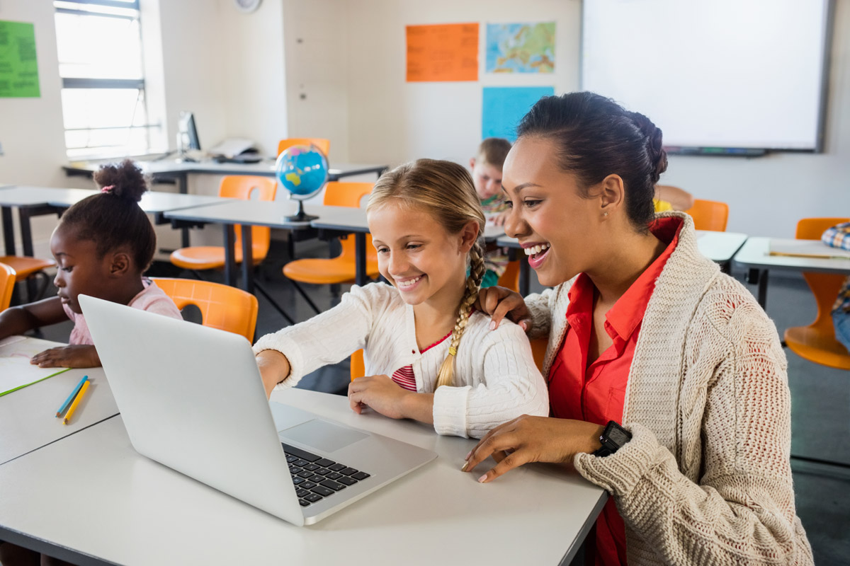 Teacher helping student at desk in classroom