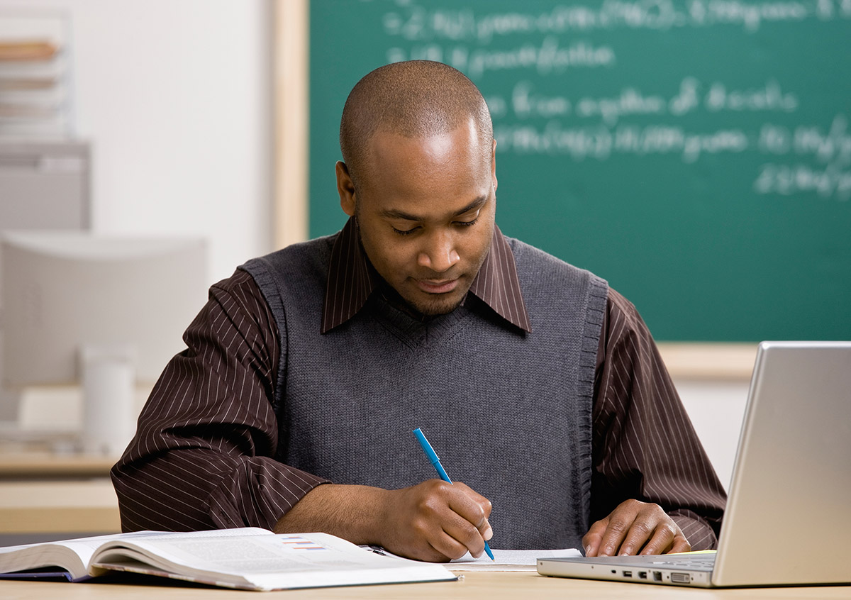 Teacher with laptop grading paper