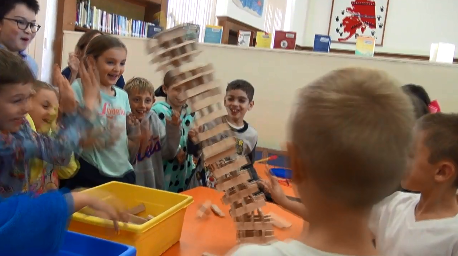 Students excited as a tower of blocks fall over.