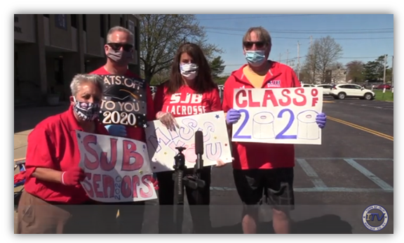 Educators holding congratulatory signs for seniors