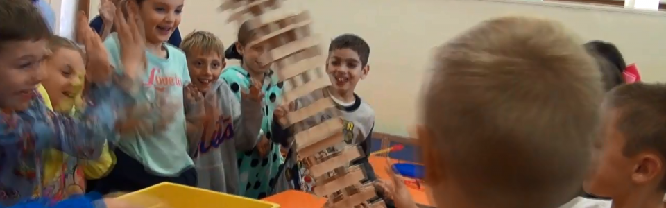 Students excited as a tower of blocks fall over.