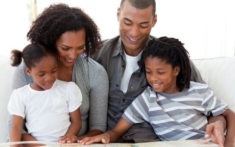 family of four reading a book together