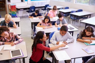 Teacher working at students desk in classroom