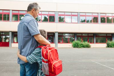 Father hugging son with backpack at school 