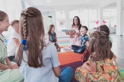 Students listening to teacher read a book out loud.