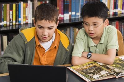 Two elementary school students working on a laptop at a library