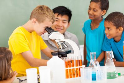 teacher and students looking in a microscope
