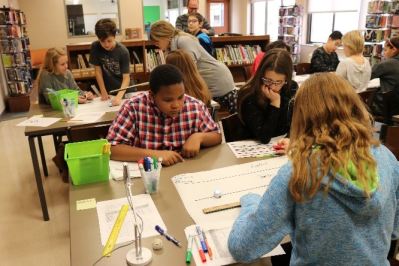 Nancy Claxton and Andrew Schmidle work with students in the library.