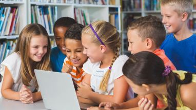 group of smiling students at laptop