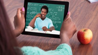 Student holding a tablet showing image of teacher