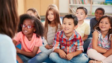 students sitting on floor listening to teacher