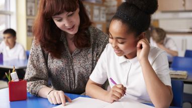 Teacher helping student at desk