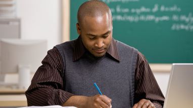 Teacher with laptop grading paper
