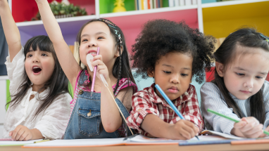 diverse elementary school students raising their hands and working at a table