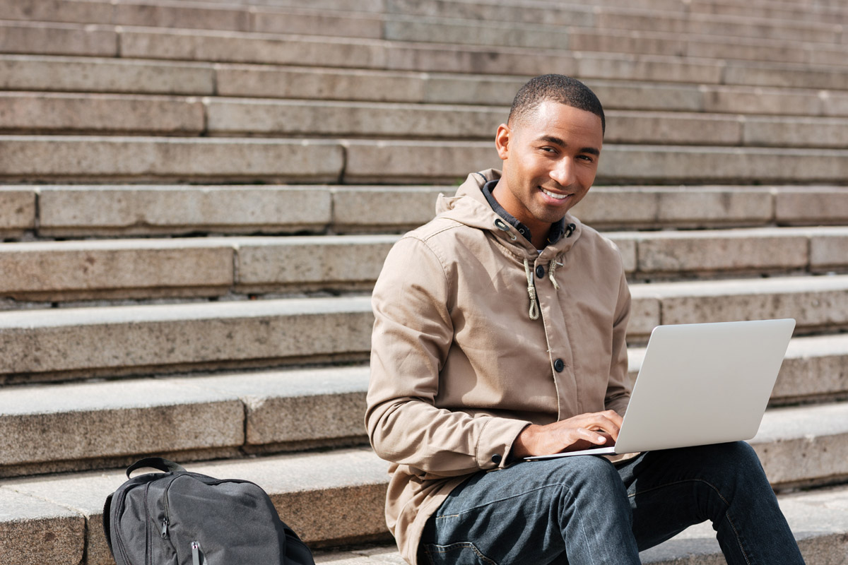 Student sitting outside on steps with laptop